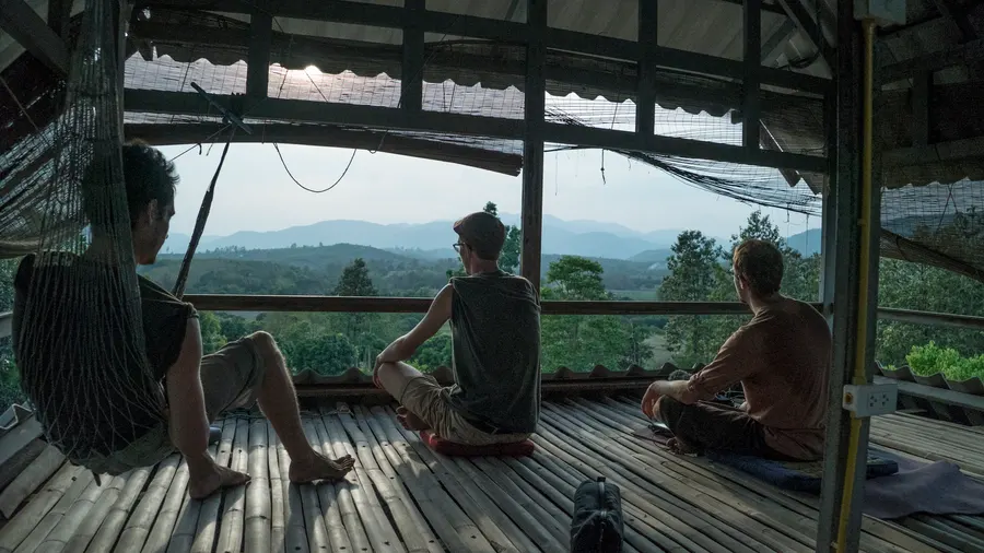 Des voyageurs sur une terrasse en bois face aux collines